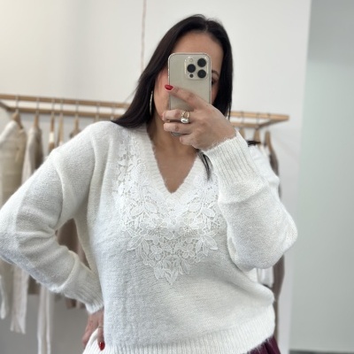 Mulher com camisola branca de malha com motivo floral e saia vinho fotografando-se com telefone