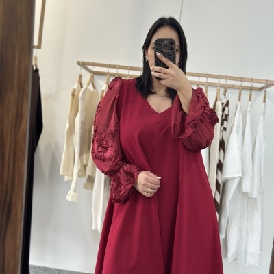 Vestido vermelho com mangas bordadas num provador de roupa
