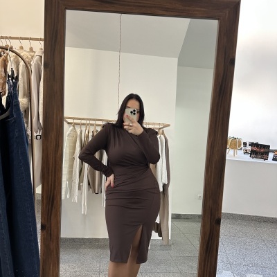 Mulher a tirar selfie no espelho vestindo vestido castanho justo com racha e botas pretas com tachas