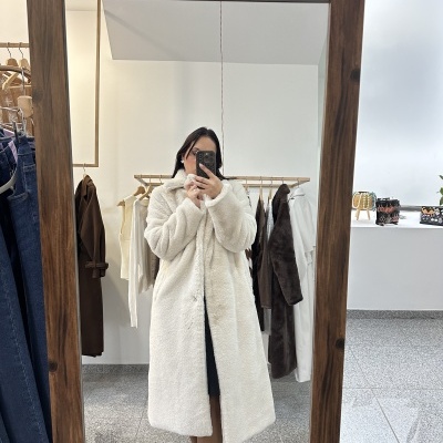 Casaco longo branco de pêlo sintético com colarinho a ser usado por pessoa, foto tirada em espelho de madeira.