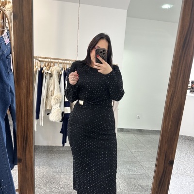 Mulher a tirar selfie num espelho usando vestido preto de pontos brancos e botas pretas