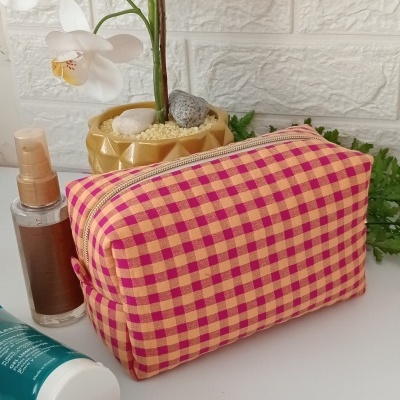 Bolsa de tela a cuadros junto a productos cosméticos y planta de orquídeas