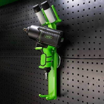 Pistola pneumática preta e verde pendurada em painel perfurado preto