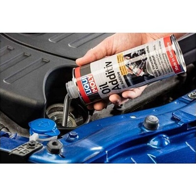 Aditivo para óleo Liqui Moly sendo colocado no motor azul de um carro.