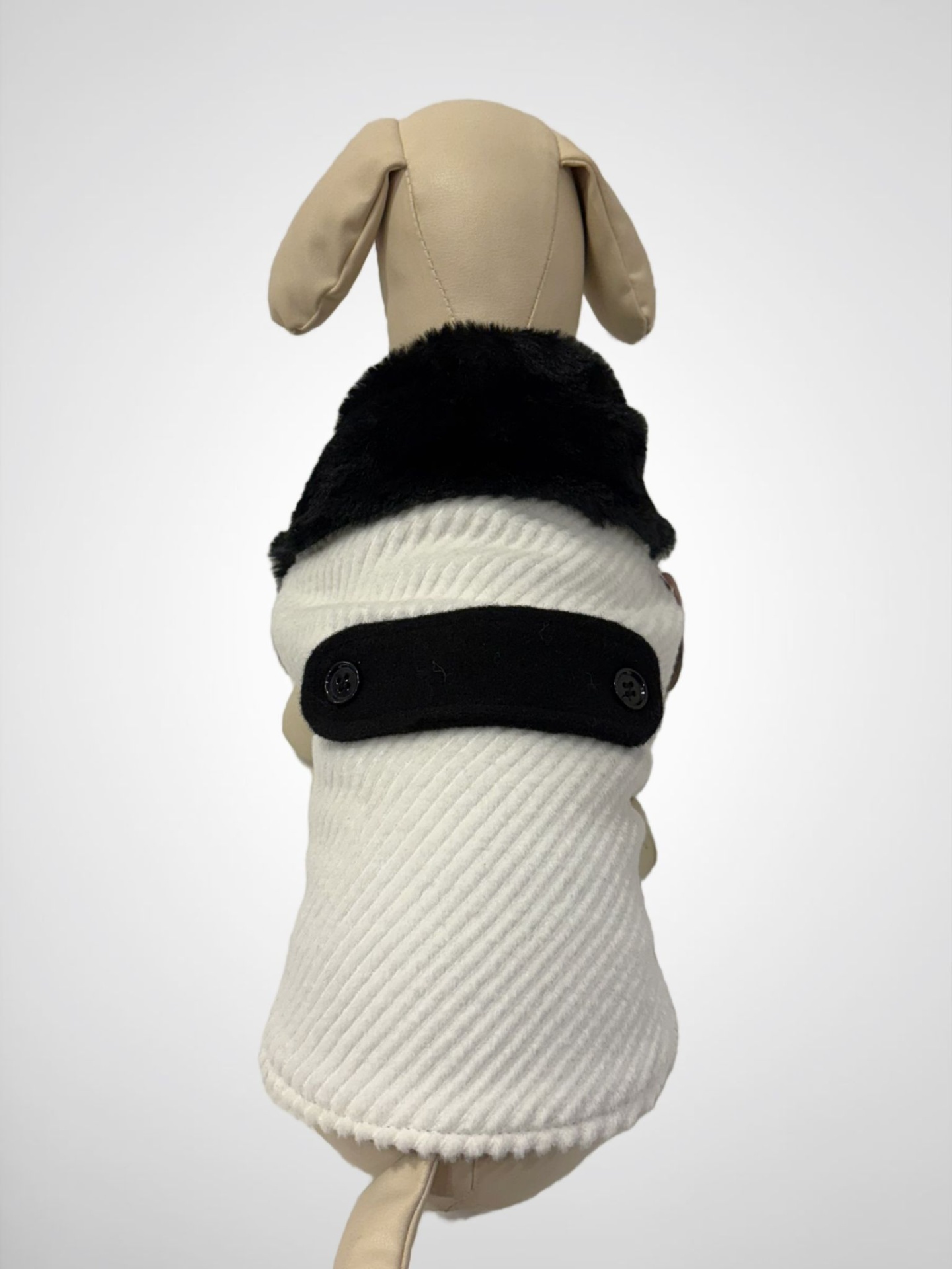Roupa de cão branca com gola preta pelúcia num manequim bege