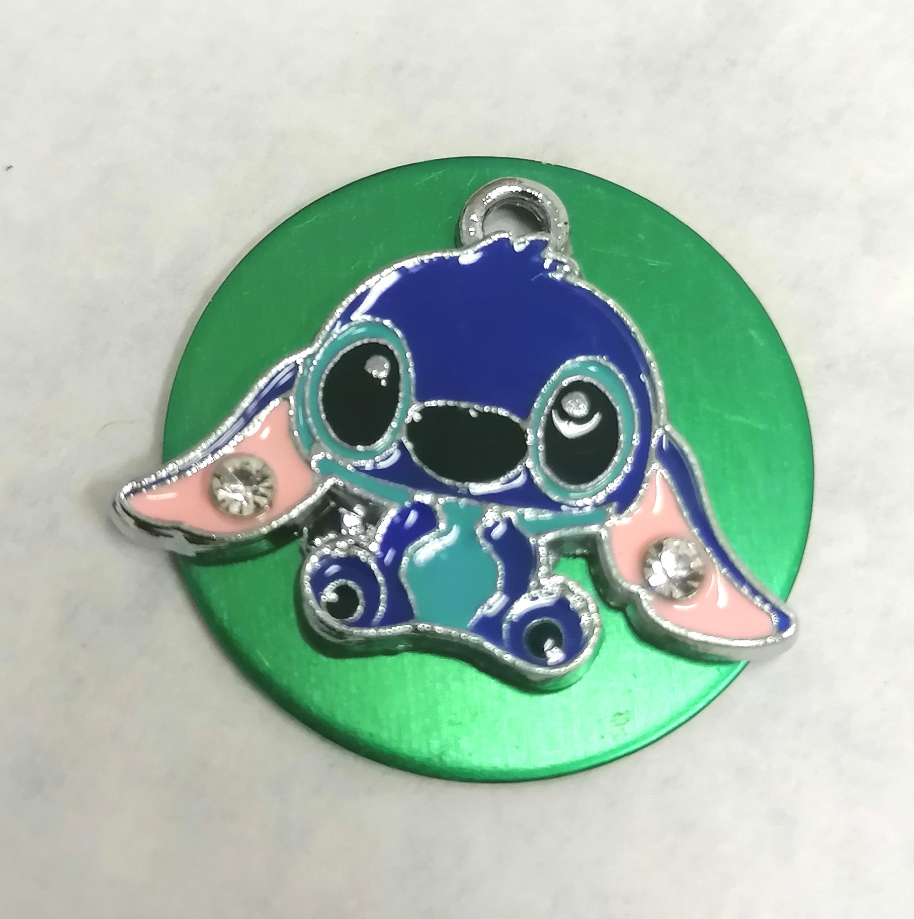 Medalha verde com pendente de personagem azul com orelhas grandes e detalhes brilhantes