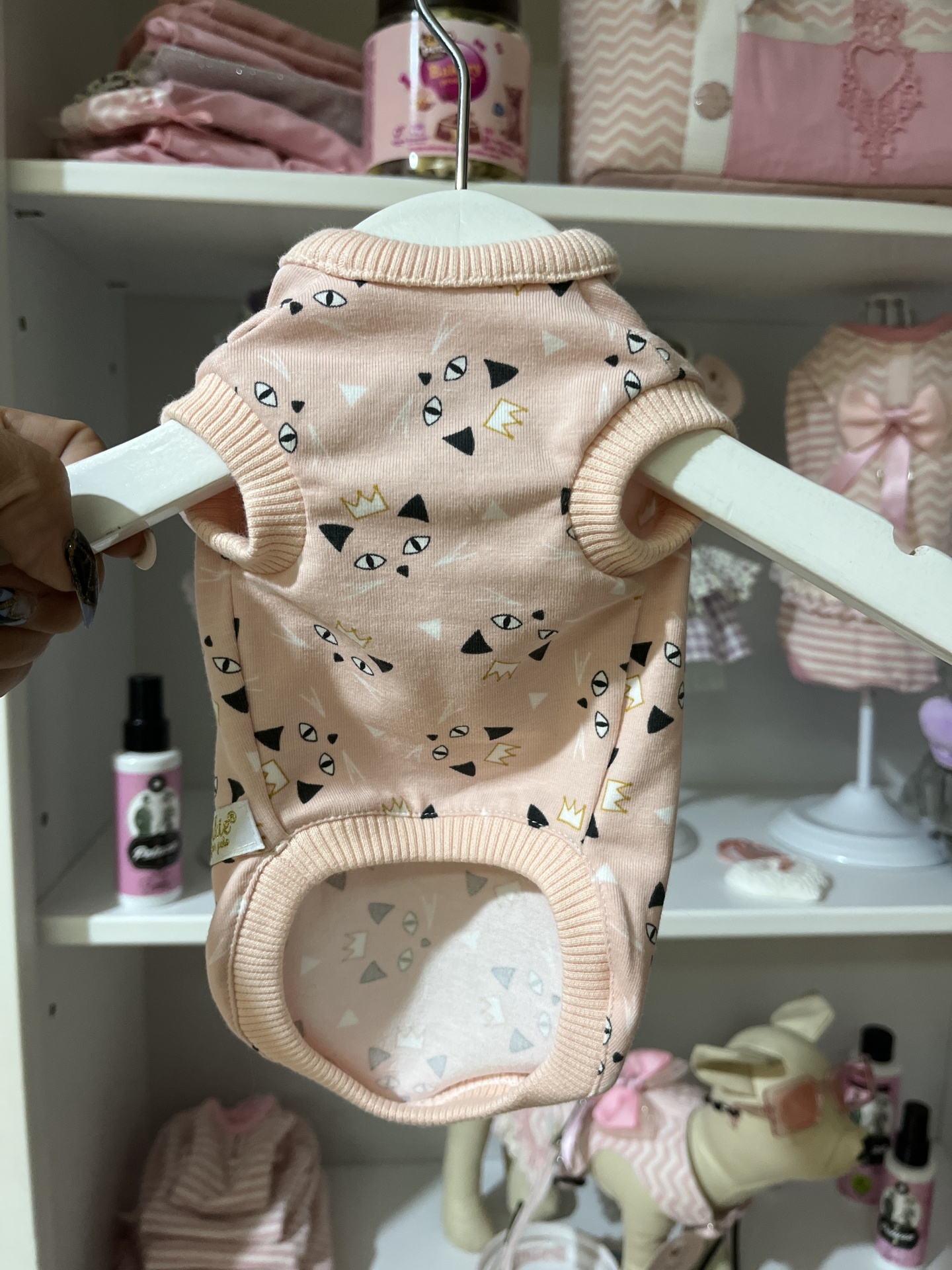 Roupa de tecido cor de rosa claro com padrões gráficos para animais de estimação pendurada em cabide