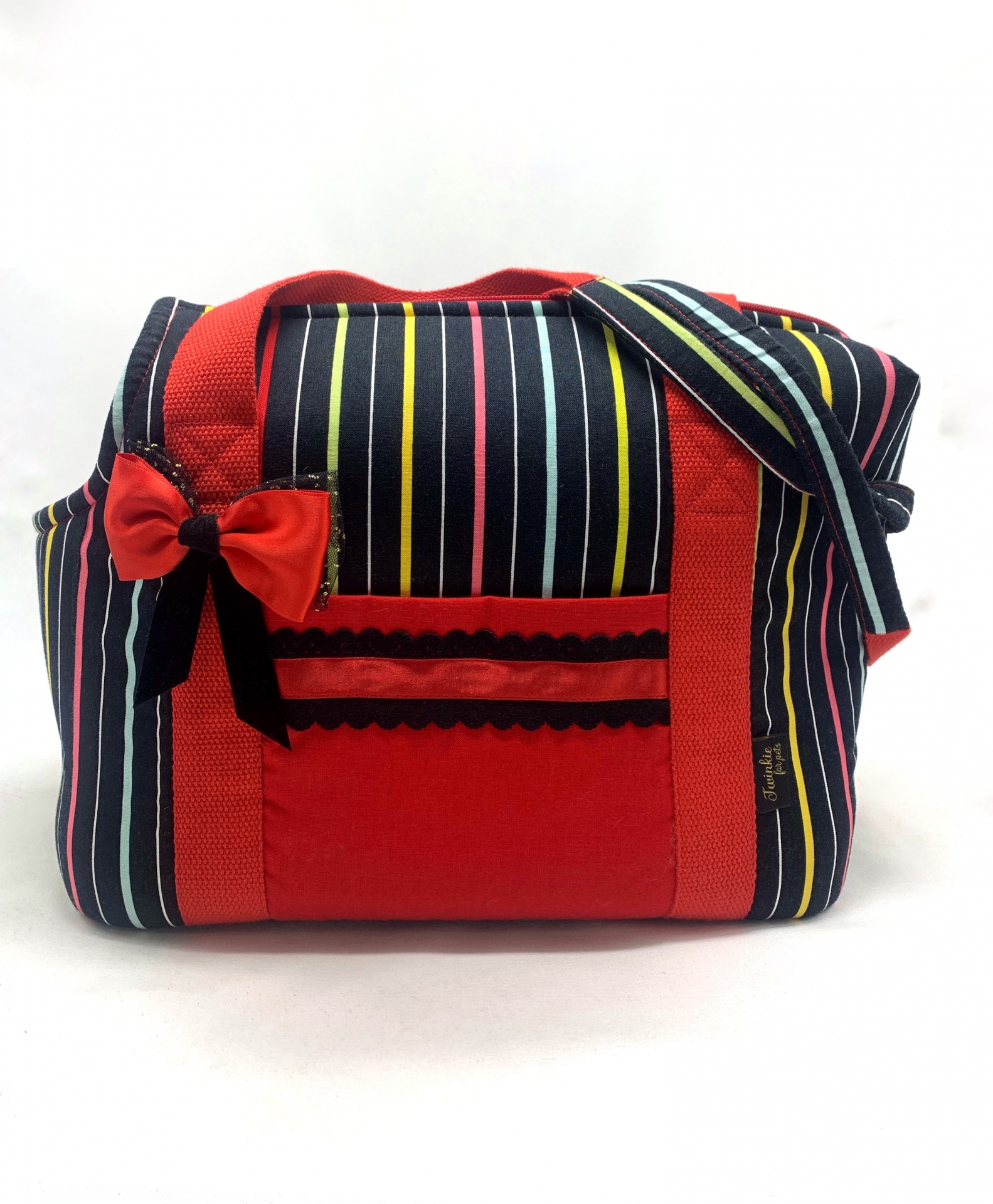 Mala de tecido com riscas verticais coloridas e detalhes em vermelho com laço