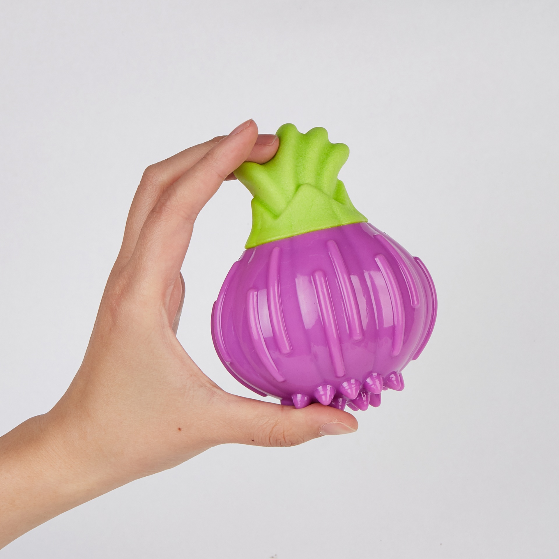 Brinquedo para animais em forma de cebola verde e roxo na mão