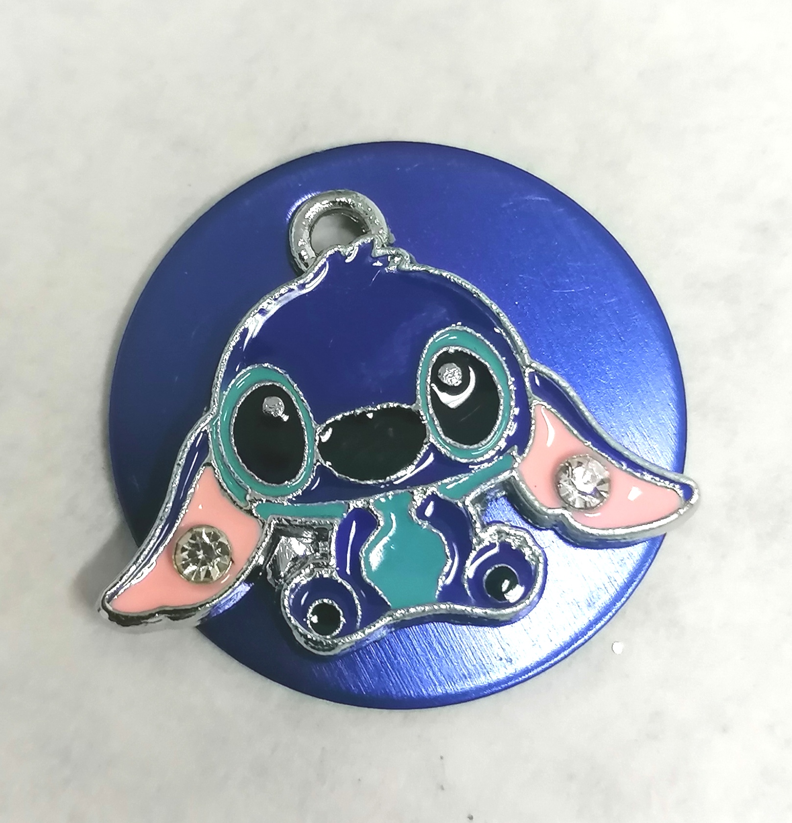 Broche azul com personagem azul e rosa em metal brilhante