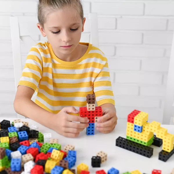Criança a brincar com blocos de construção coloridos sobre mesa branca