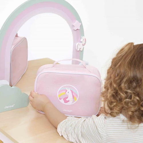 Bolsa rosa para criança com unicórnio e espelho de apoio em mesa de madeira clara