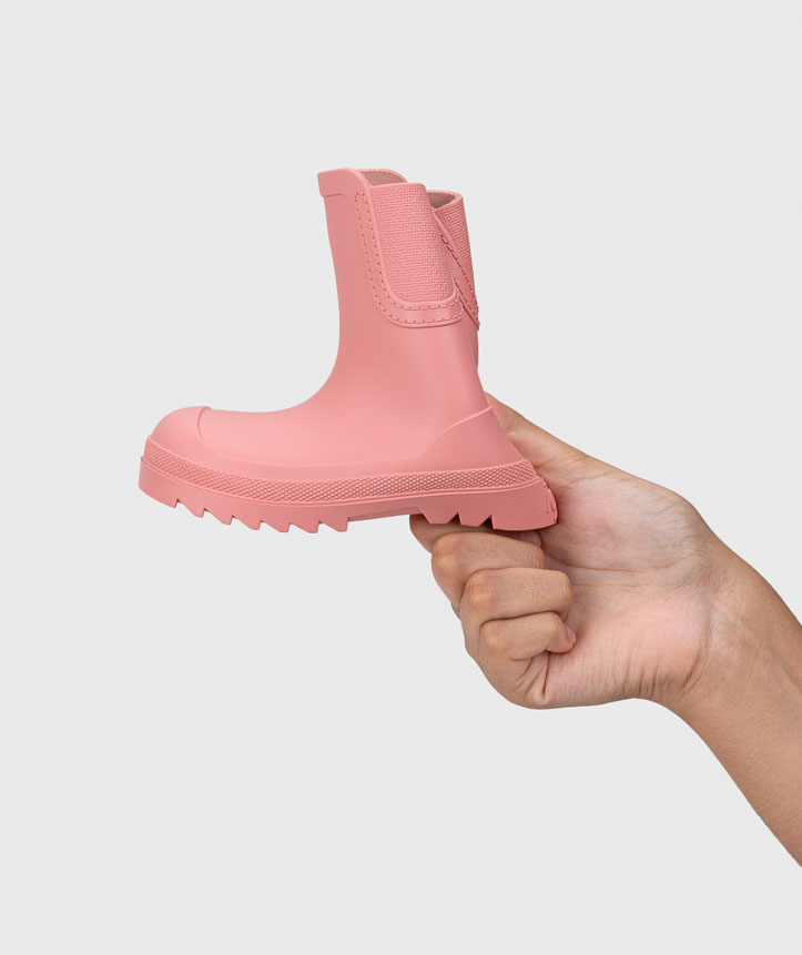 Bota infantil rosa em silicone com sola robusta segura por mão