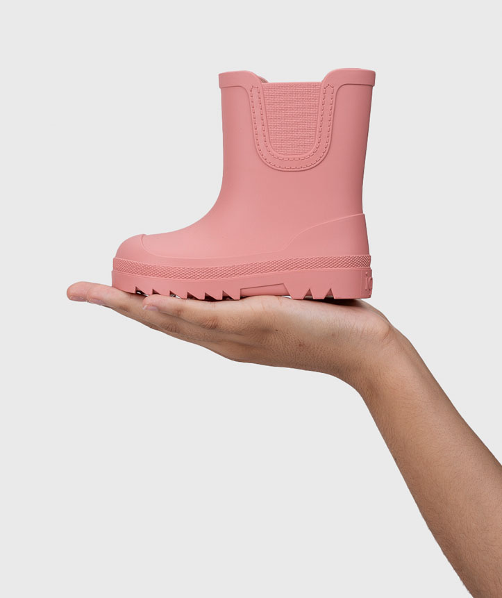 Bota infantil rosa em borracha com sola grossa na mão