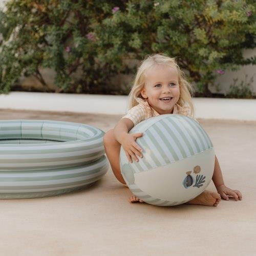 Criança a brincar com bola insuflável verde e branca ao lado de piscina insuflável listrada
