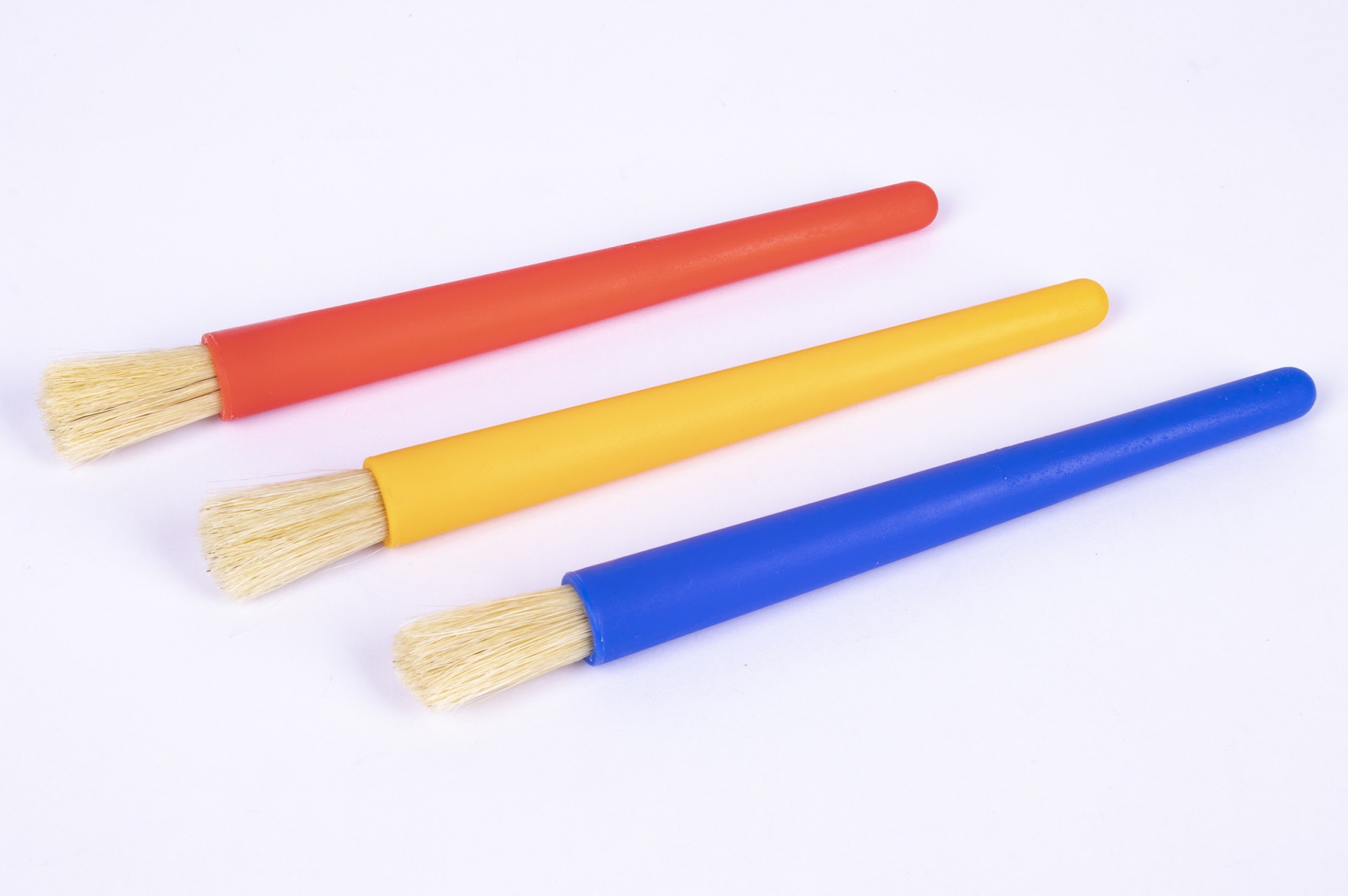 Três pincéis com cabos coloridos em laranja, amarelo e azul e cerdas claras.