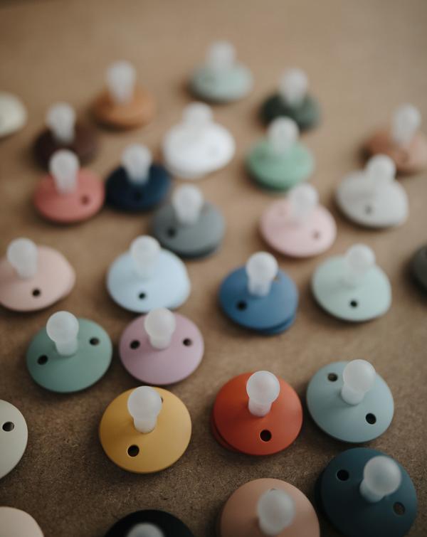 Biberões para bebés com chupetas coloridas em tons pastel