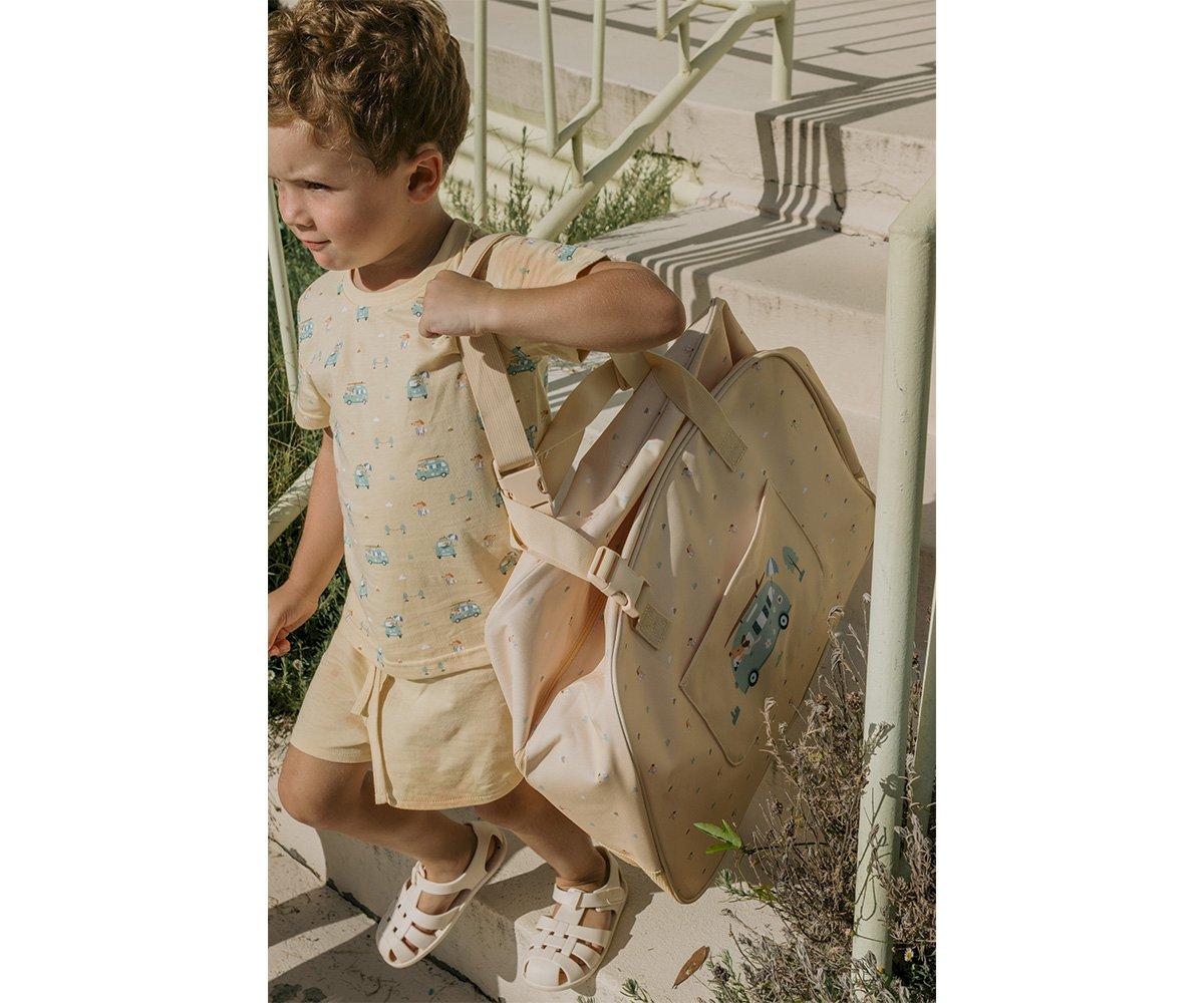 Criança com mochila rosa claro e roupa bege ao ar livre