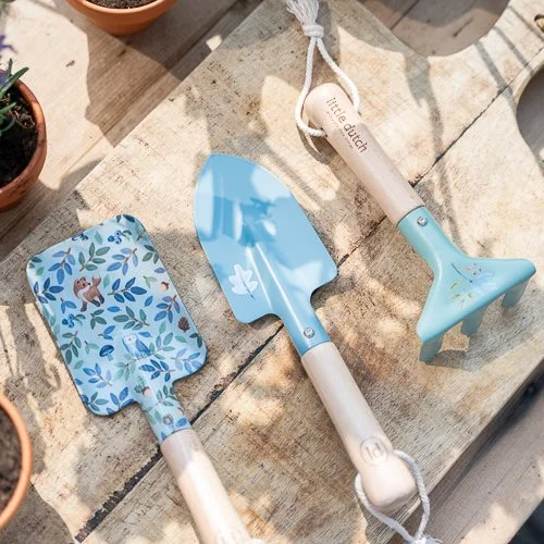 Três ferramentas de jardinagem com cabos de madeira e metal azul com padrão floral em madeira clara