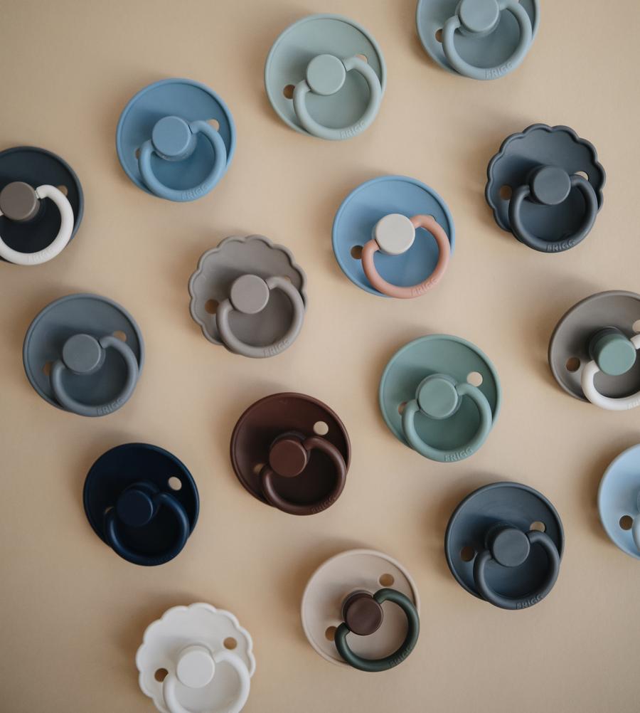 Chupetas coloridas de silicone em fundo bege