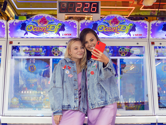 Duas mulheres tirando selfie em frente a máquina de jogos arcade Ocean Elf