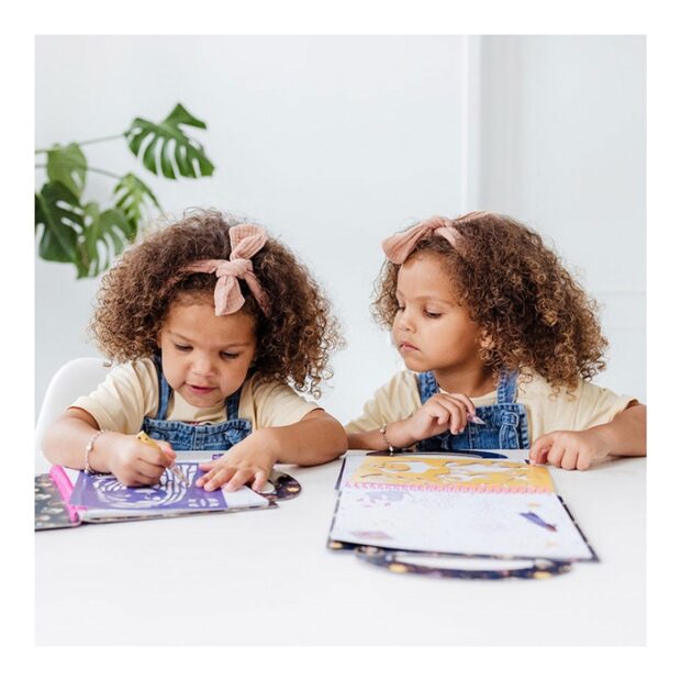 Duas crianças a desenhar numa mesa branca