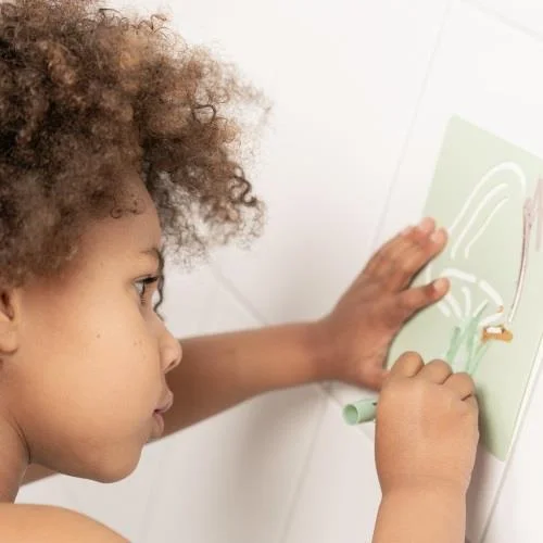 Criança a desenhar na parede com giz de cor verde