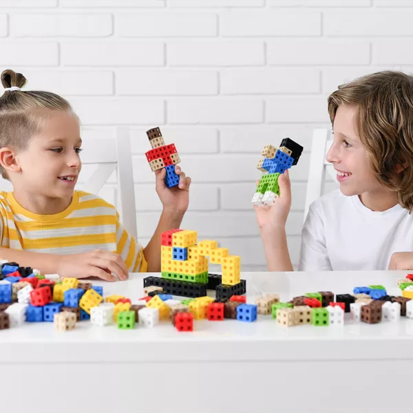 Crianças a brincar com blocos de construção coloridos numa mesa branca