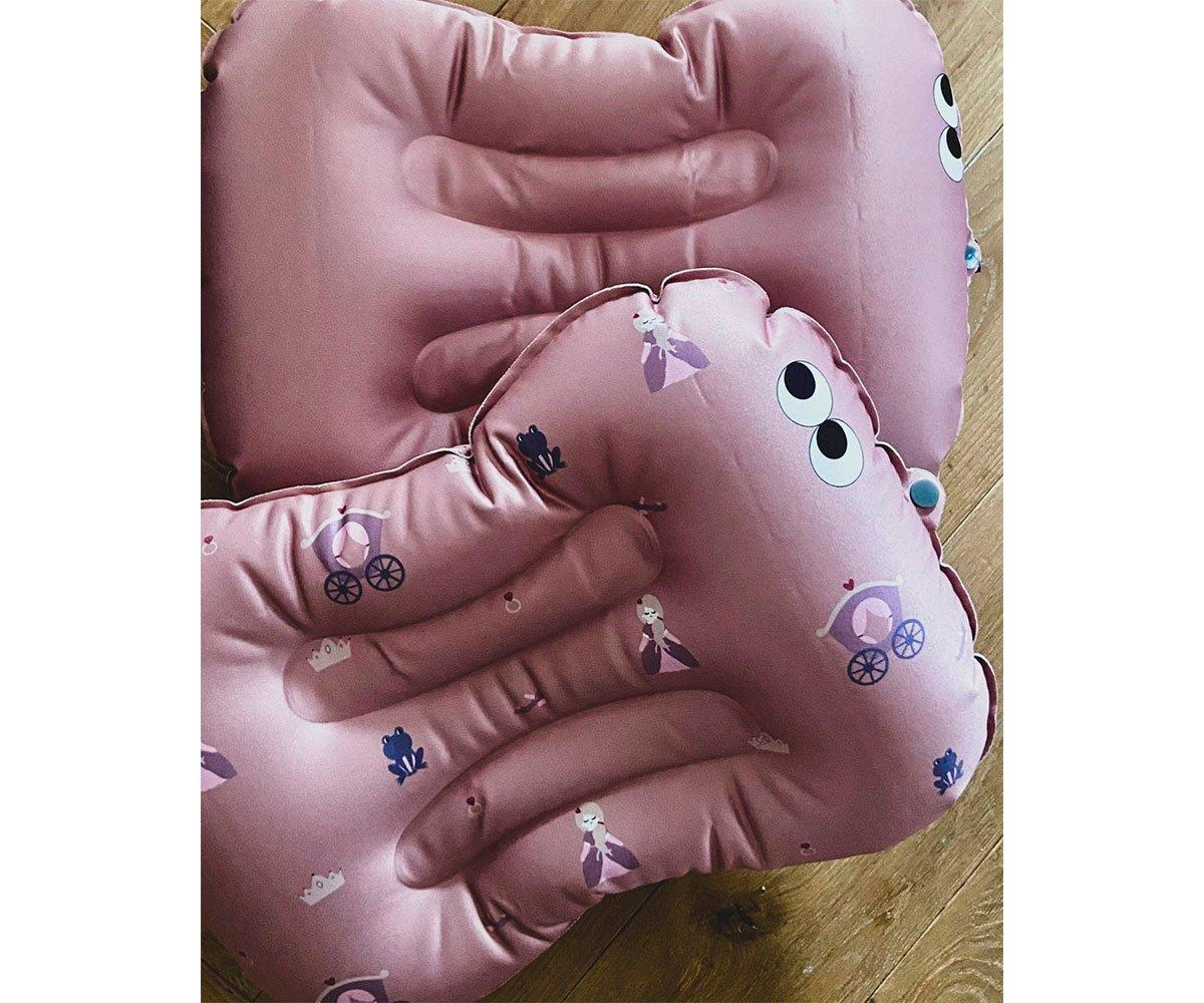Almofadas cor-de-rosa em formato de mãos com padrão de carrinhos de bebé e meninas
