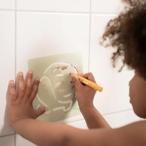 Criança a desenhar com estêncil sobre azulejos brancos