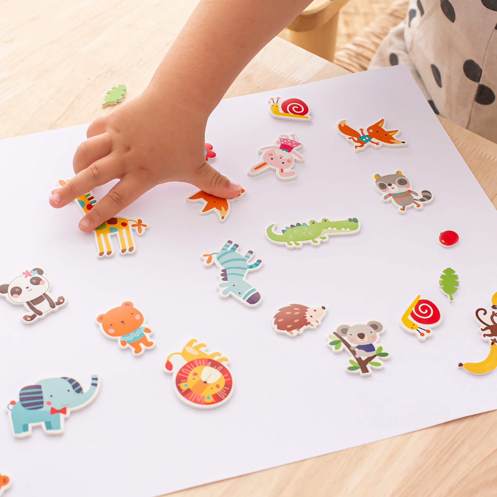 Autocolantes de animais coloridos sobre folha branca e mão infantil