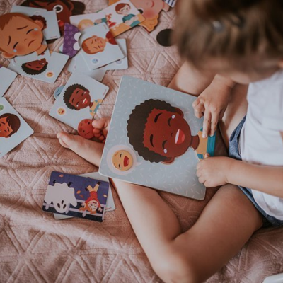 Criança a brincar com cartões ilustrados de rostos diversos