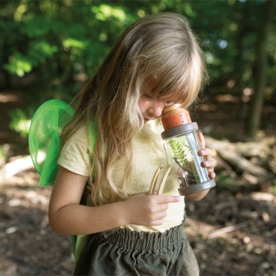 Criança com recipiente transparente numa floresta
