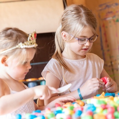Duas crianças brincando com peças coloridas de construção numa mesa de madeira