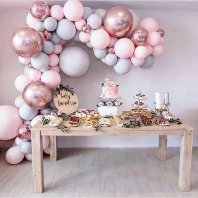 Arco de balões rosa e cinza decorando mesa de festa com bolo e placa 'baby bavlano'
