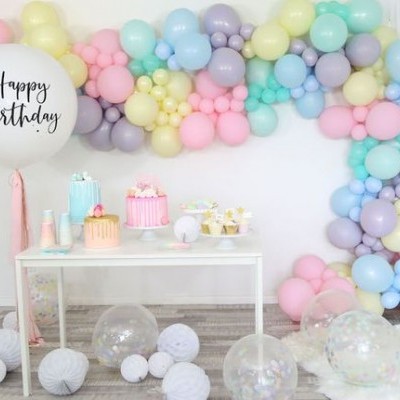 Decoração de festa com balões coloridos e mesas com bolos