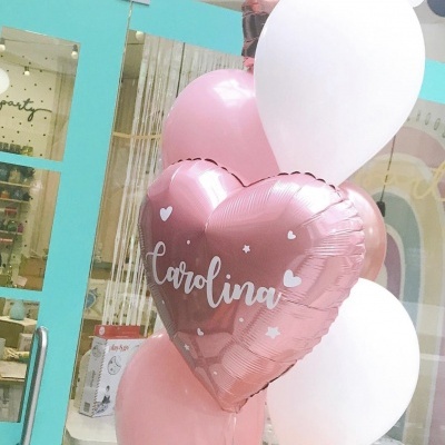 Balões cor-de-rosa e brancos, incluindo balão cor-de-rosa metálico em forma de coração com o nome 'carolina'.