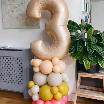 Balão número 3 champagne com base multicolorida de balões em ambiente interior