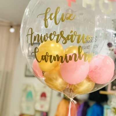 Balão transparente com bolas douradas e cor-de-rosa e texto dourado de feliz aniversário