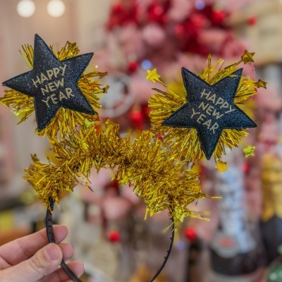 Aro de cabelo preto com estrelas decorativas douradas e texto HAPPY NEW YEAR.