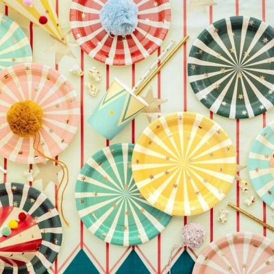 Pratos e chapéus de festa coloridos com padrões de riscas e decoração festiva