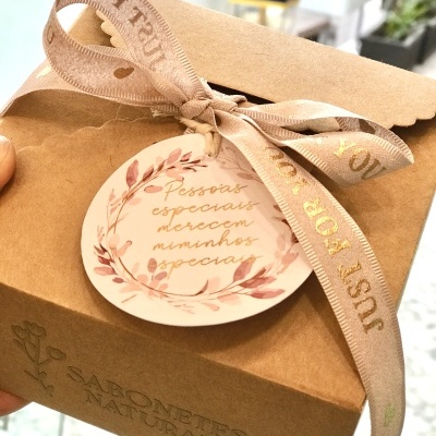 Caixa de papel kraft decorada com etiqueta redonda e laço bege com texto dourado