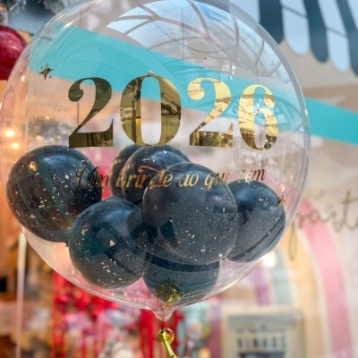 Balão transparente com balões pretos internos e texto dourado 2026