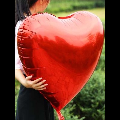 balão vermelho em forma de coração nas mãos de pessoa ao ar livre