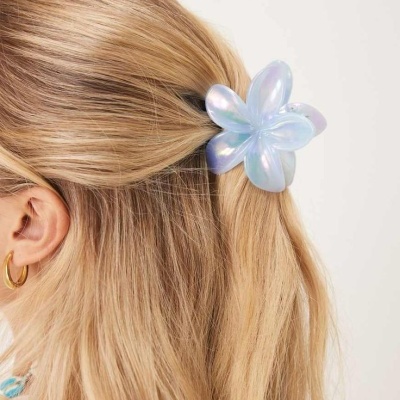 Presilha de flor iridescente azul em cabelo loiro