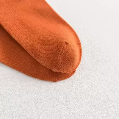 Par de meias cor castanho alaranjado em tecido fino sobre superfície branca