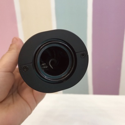 Objeto cilíndrico preto em mão com fundo colorido às riscas