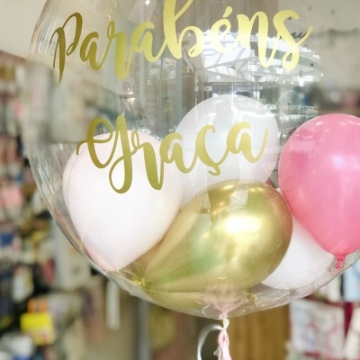 Balão transparente com balões coloridos e texto dourado em loja