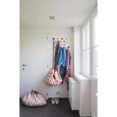 Entrada de casa com cabide branco e várias roupas penduradas ao lado de uma janela grande.