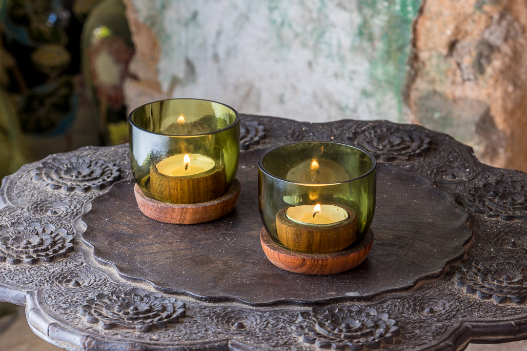 Suporte de vela Taa pequena Dois porta-velas verdes em vidro com base de madeira sobre prato metálico decorativo